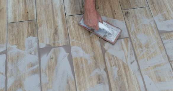A man applying the grout on the tiles and other side some grout has been dried